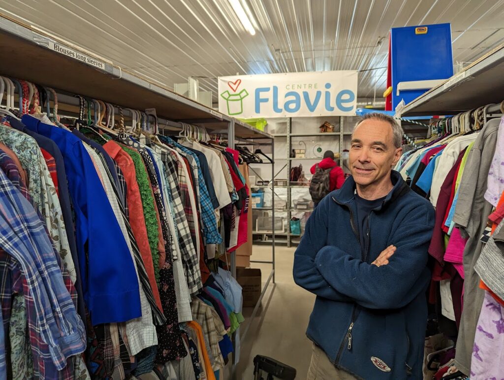A man stands among a rack of clothing at Centre Flavie's warehouse