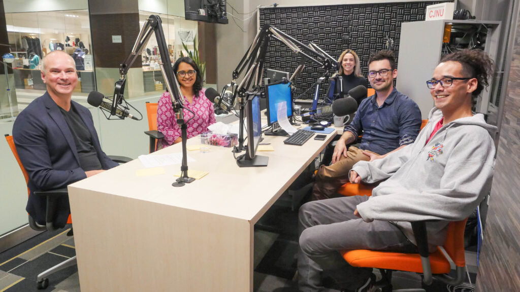Five people sit around a table with microphones in CJNU's studio. From left to right: Ashley Smith, Shereen Denetto, Shauna Turnley, Nolan Bicknell, Michael Redhead Champagne