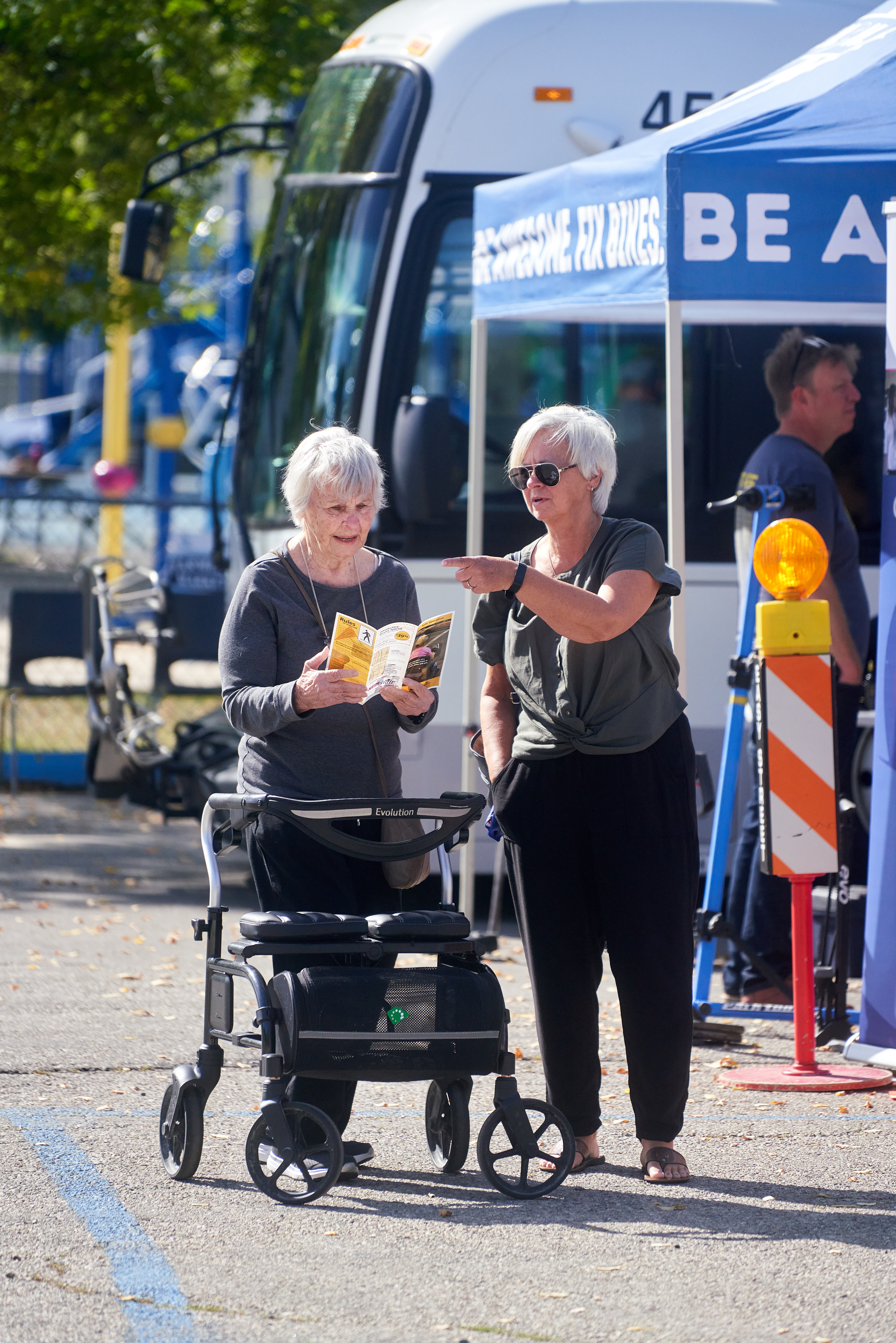 Two people stand in front of a bus during a mobility fair for older adults.