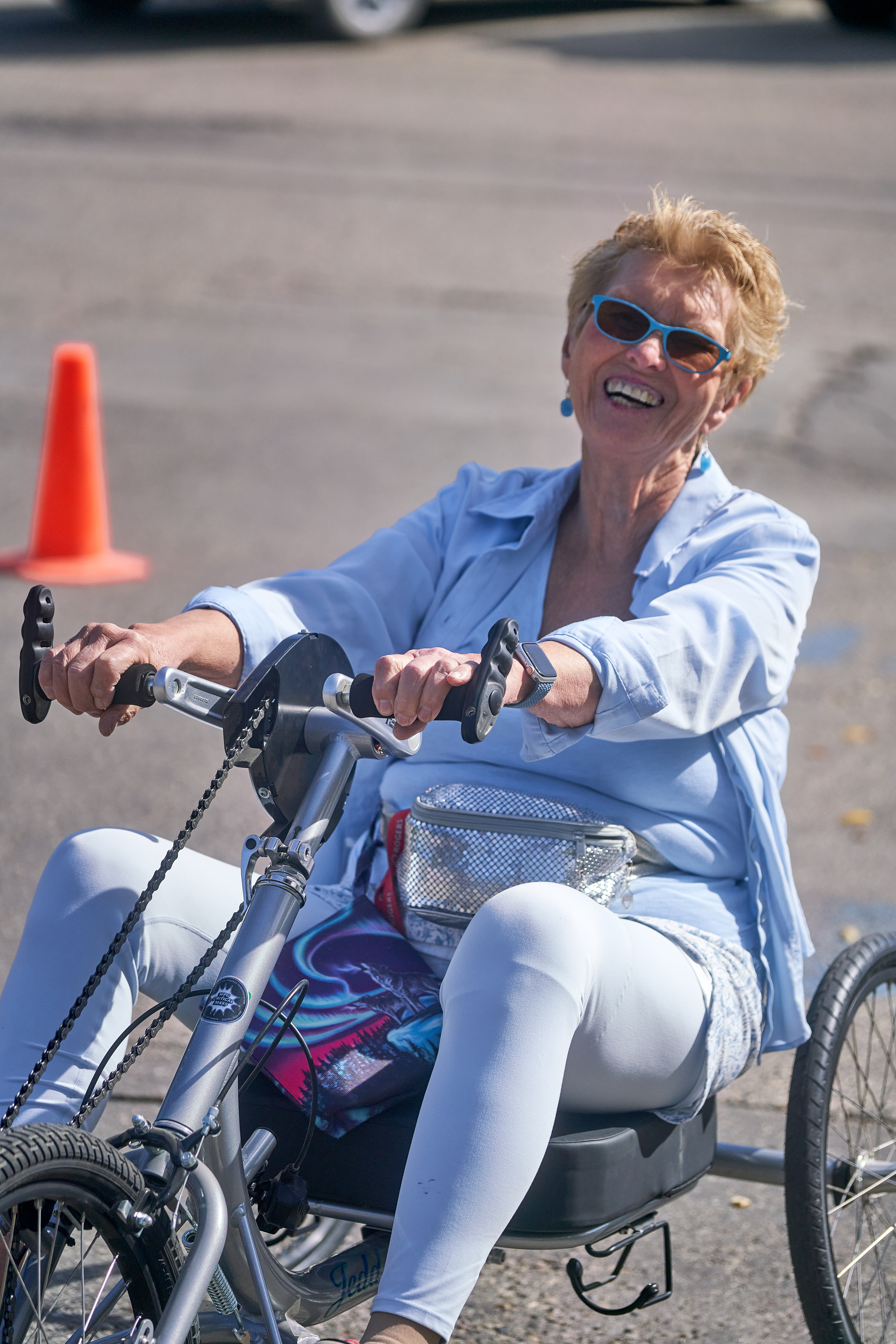 A woman with short hair and sunglasses rides a tricycle.