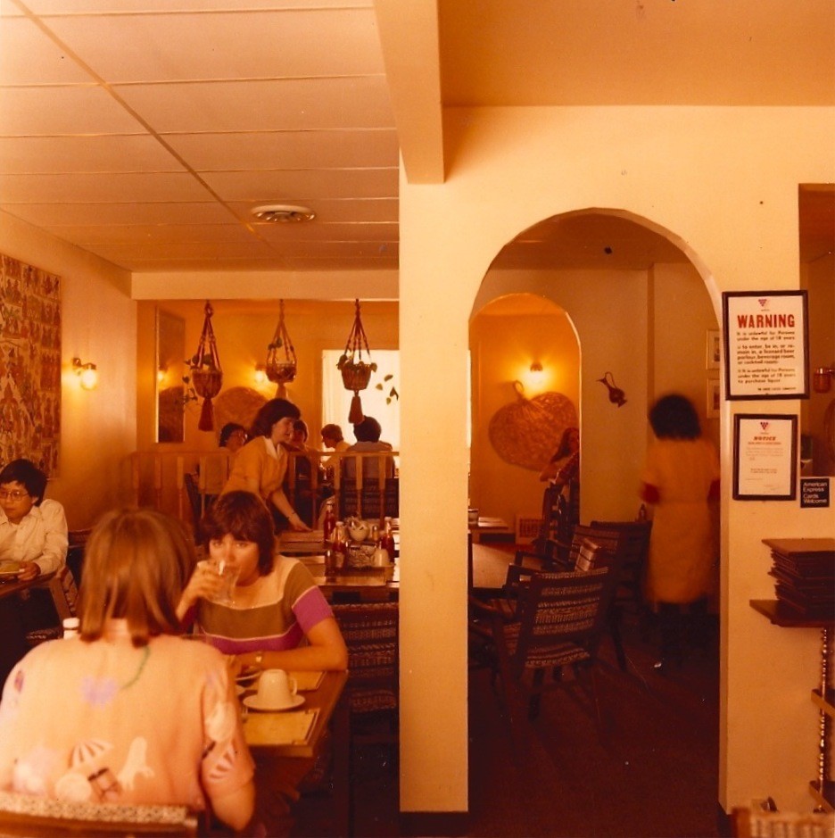 A film photo with a yellow tinge of diners inside India Gardens.