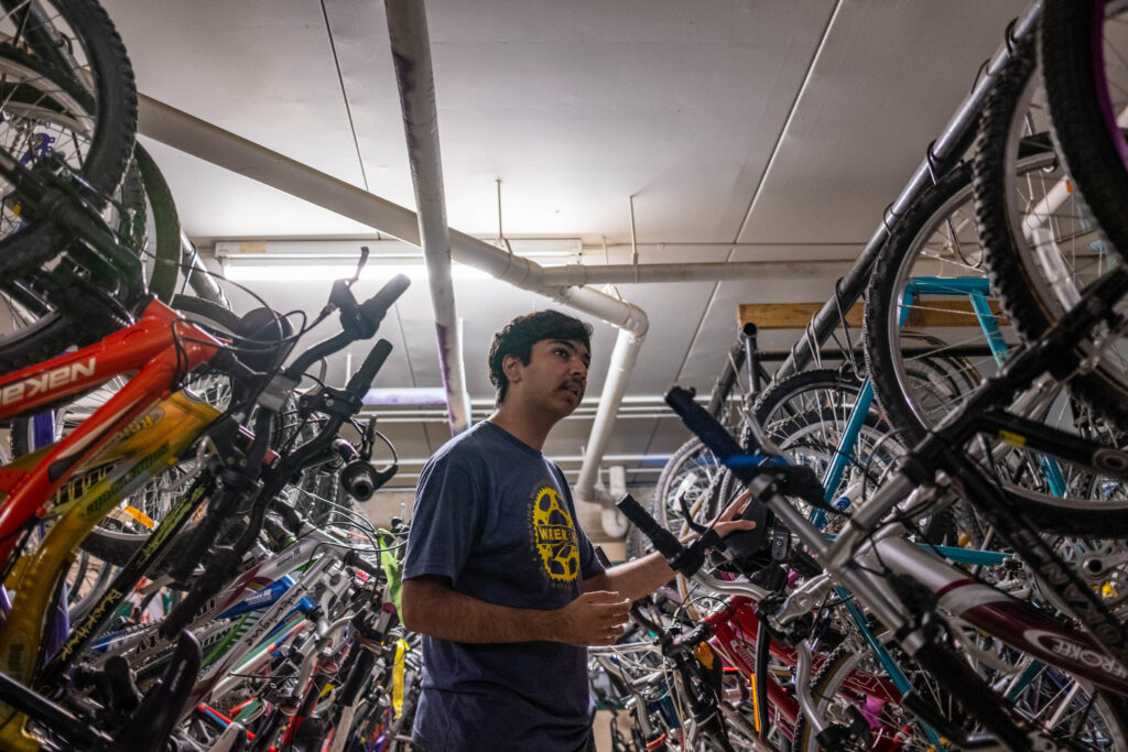 A Summer Internship Program participant stands among racks of bicycles at The WRENCH.