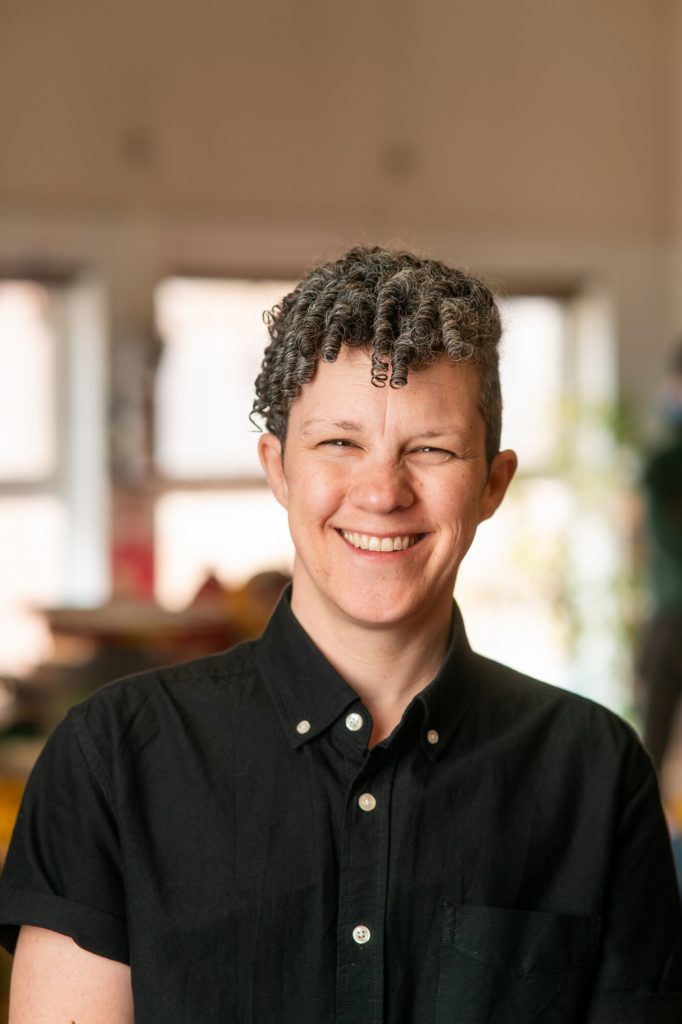 Carey Anderson smiles while standing inside a bright community learning space.