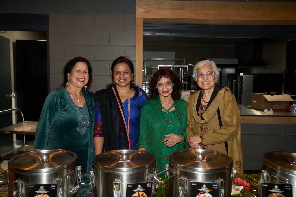 Volunteers serve food to guests during a community event.