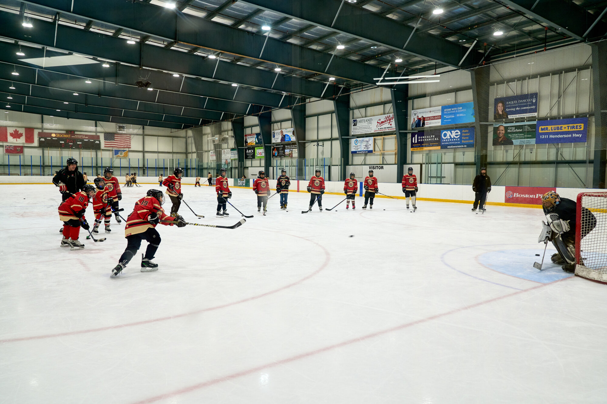 HEROS hockey participants line up on the ice during a shooting and skating drill at an indoor arena.