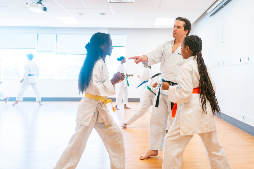 A karate instructor speaks with two young students during a martial arts class.