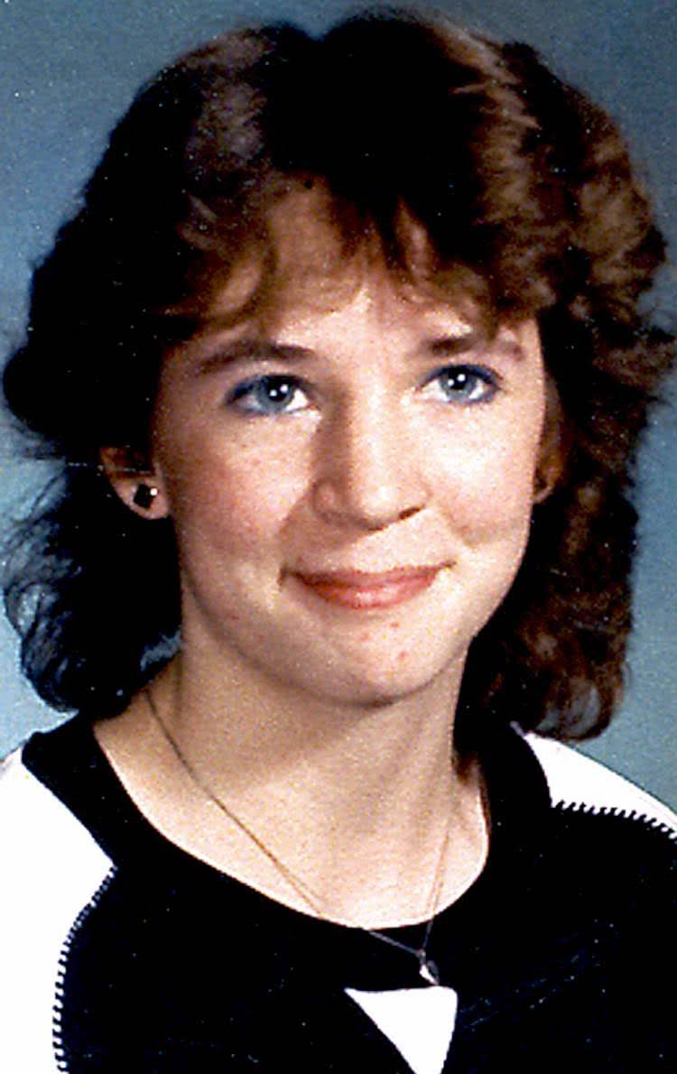 A school portrait of a young woman with dark curly hair, wearing a black-and-white top and smiling softly at the camera.