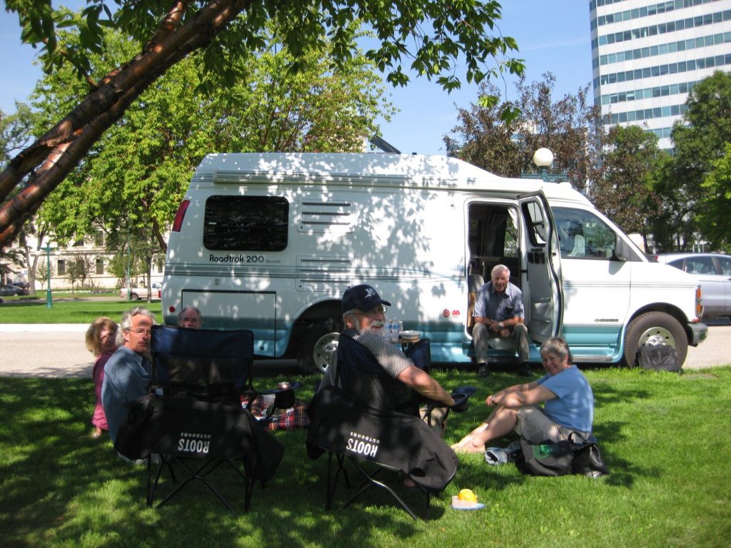 A group of people gathers outdoors beside an RV in downtown Winnipeg.