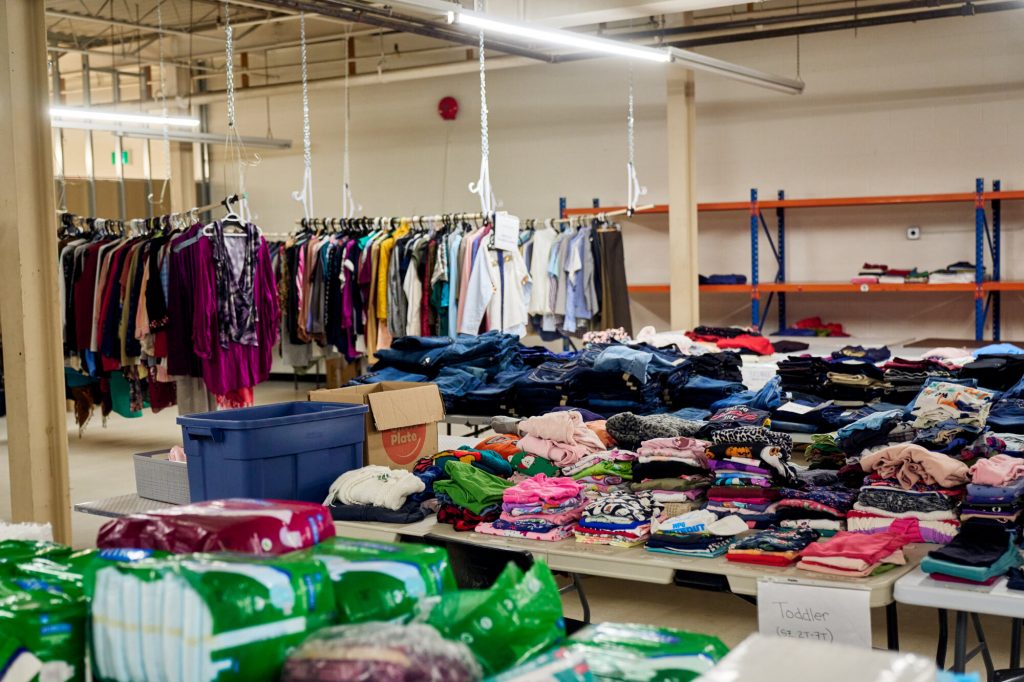 Tables of sorted clothing, diapers and household items in Linking Hope’s warehouse, ready to be redistributed to local agencies.