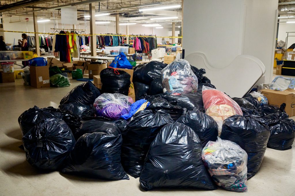 Bags of donated clothing piled in the Linking Hope warehouse, ready to be picked up by local agencies.