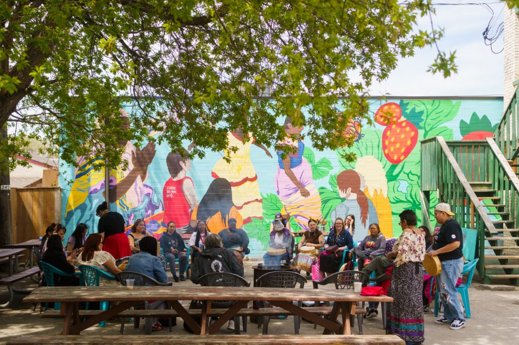 A group of people having a discussion by a beautiful community mural.