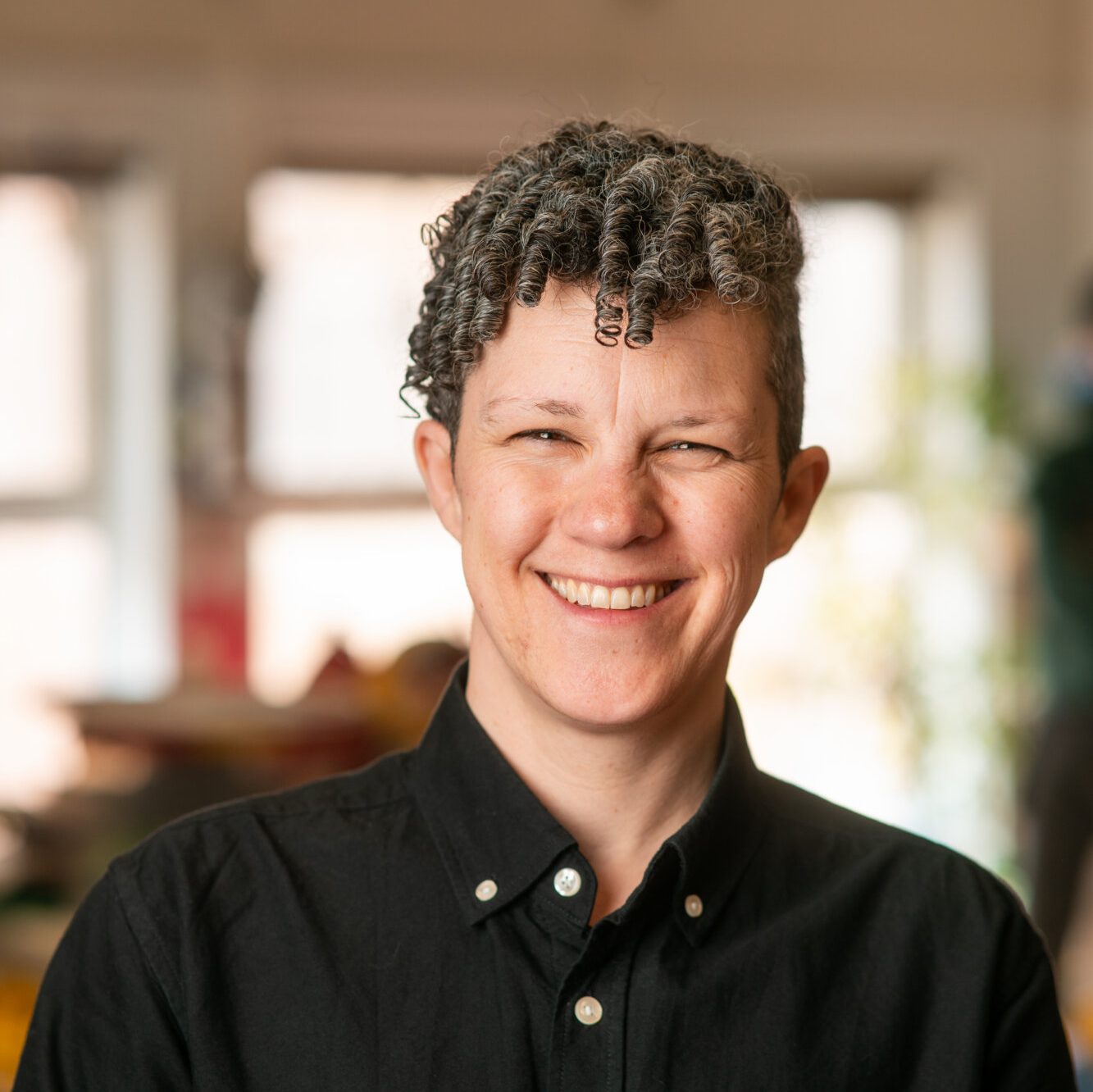 Carey Richards smiles while standing inside a bright community learning space.